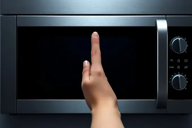 Painel digital de micro-ondas apagado com dedo pairando sobre superfície sem resposta, indicando falha nos controles.